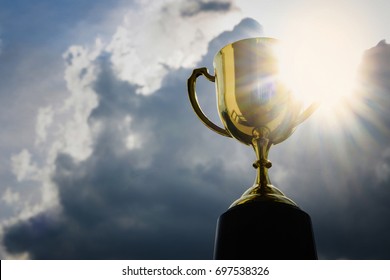 Gold cup winner trophy on sky background , Award winning trophy for a champion in a competition and best business. Concept for winning or success
