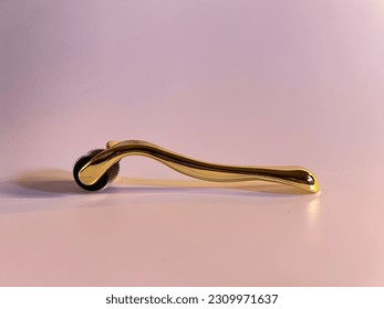 Gold Dermaroller for needleless mesotherapy. Aesthetic medicine treatments. On a pink background. Goldroller - Shutterstock ID 2309971637