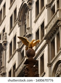 gold eagle with wings open in front of brown building