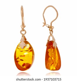Gold earrings with large amber. Jewelry close-up on a white background with reflection. A gift for a woman.