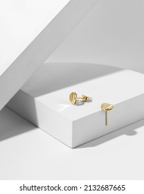 Gold earrings on white background. Still life and creative photo with shadows.