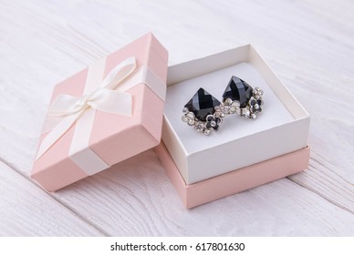 Gold Earrings With Onyx In The Gift Box On White Wooden Background