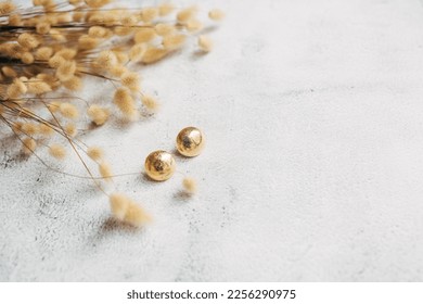 Gold earrings rabbit bunny tales grass dry flowers on white background. Minimal fashion composition. jewelry concept. Flat lay. Copy space. - Shutterstock ID 2256290975