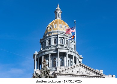 Gold exterior dome of the Colorado State Capitol building in Denver with flags flying