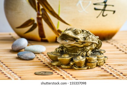 Gold feng-shui frog statuette on a bamboo mat