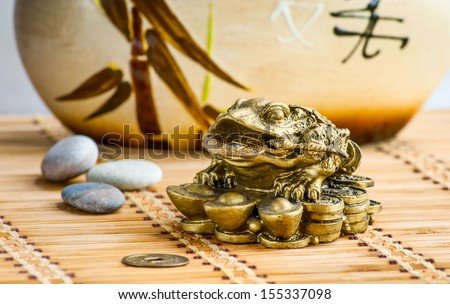 Gold feng-shui frog statuette on a bamboo mat