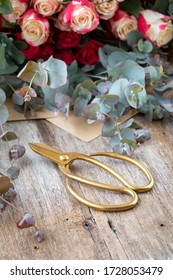 Gold Florist Scissors With Rose And Gum Leaves Background.