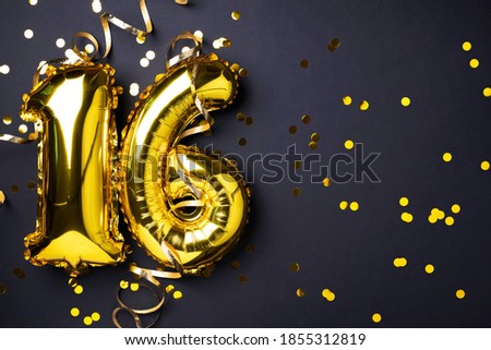 Gold foil balloon number, digit sixteen. Birthday greeting card, inscription 16. Anniversary celebration event. Banner. Stylish golden numeral, light bokeh, glitter, black background. Numerical digit.