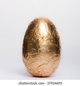 Gold Foil Wrapped Chocolate Easter Egg Isolated Against White Background