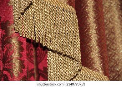 Gold Fringe On The Background Of A Red Silk Curtain