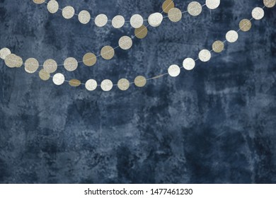 Gold garlands on a smoky dark blue background. Birthday and holiday decor.