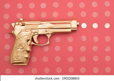 Gold Gun On Pink Bakground. Flat Lay