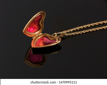 Gold heart locket necklace open and close up on black background