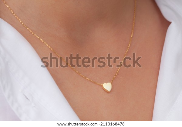 Gold heart necklace on neck of attractive white\
dress girl. Personalized necklace image. Jewelry photo for e\
commerce, online sale, social\
media.