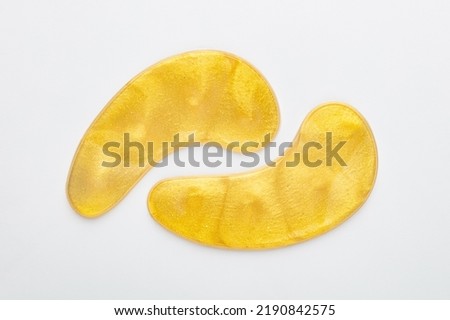 Gold hydrogel eye patches on white background.