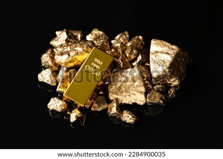 Gold ingot and nuggets on black background