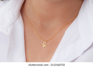 Gold Initial Necklace On Neck Of Attractive White Dress Girl. Personalized Necklace Image. Jewelry Photo For E Commerce, Online Sale, Social Media.