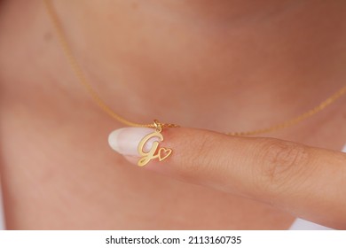 Gold Initial Necklace On Neck Of Attractive White Dress Girl. Personalized Necklace Image. Jewelry Photo For E Commerce, Online Sale, Social Media.