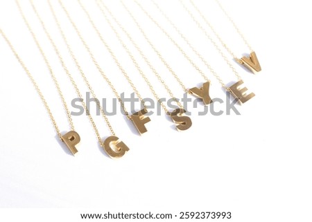 Gold initial necklaces featuring delicate letters on dainty chains. Minimalist gold letter necklaces arranged on a white background. Perfect for personalized jewelry lovers and elegant fashion styling