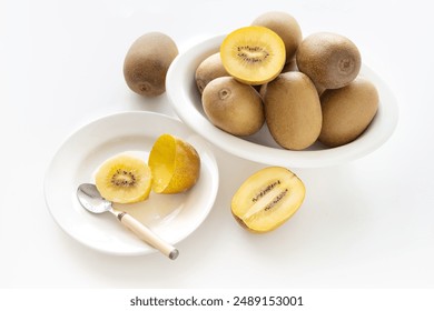 Gold kiwis cut on wood cutting board, kiwi slices and spoons - Powered by Shutterstock
