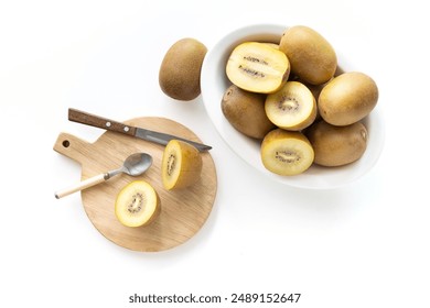 Gold Kiwis cut on a wooden cutting board. Fruit knife, spoon, white background - Powered by Shutterstock