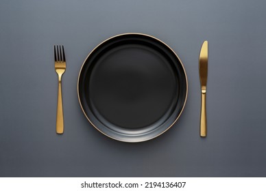 Gold knives and forks on a black background, empty black plate. Beautiful gold cutlery. View from above. - Shutterstock ID 2194136407