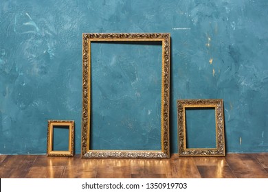 Gold large frame on a blue wall background. Decorative element. Vintage gold plated picture frame. Vintage photo zone.
