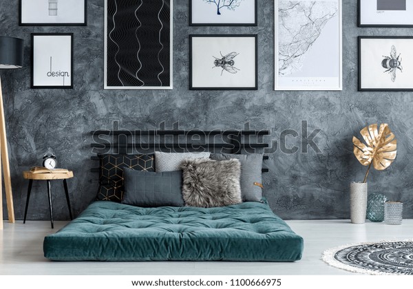 Gold leaf near green mattress\
with pillows in modern bedroom interior with gallery of\
posters