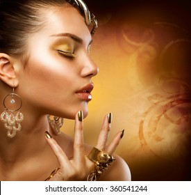 Gold Makeup. Fashion Girl Portrait with golden accessories, earrings, ring and bracelets. Gold make up