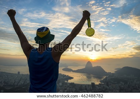 Gold medal champion athlete standing outdoors in silhouette at a golden sunrise skyline overlook in Rio de Janeiro, Brazil