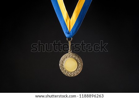 Gold Medal, Clear Gold Medal with Blue and Yellow Ribbon on black background, First Place, copy space