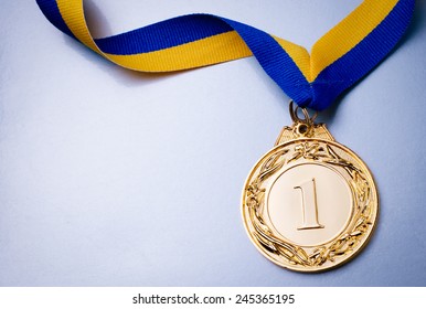 Gold medal in the foreground on yellow blue ribbon