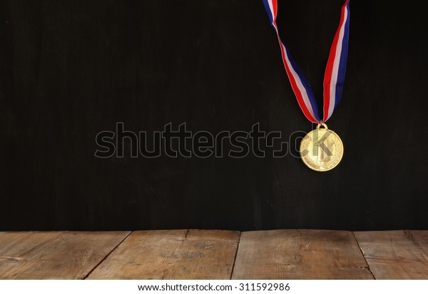 Gold medal over textured black\
background with room for text, winning and success\
concept