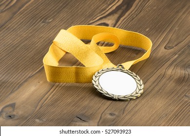 Gold Medal With White Placeholder And Yellow Ribbon On Wooden Textured Table