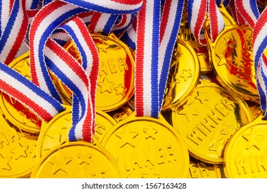 A Lot Of Gold Medals With Ribbons As Background