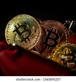 Gold metal Bitcoins in red leather wallet on black background