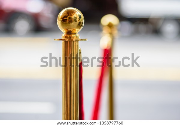 Gold metal\
posts holding a red velvet rope as is often used at event openings,\
awards ceremonies and VIP\
areas