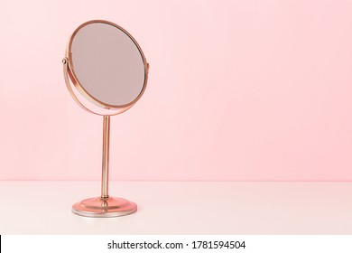 Gold mirroron pink background. Vanity table concept. Minimal composition. Copy space for your text.