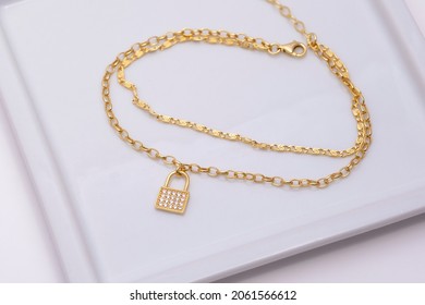 Gold Necklace On A White Plate On A Soft White Background.