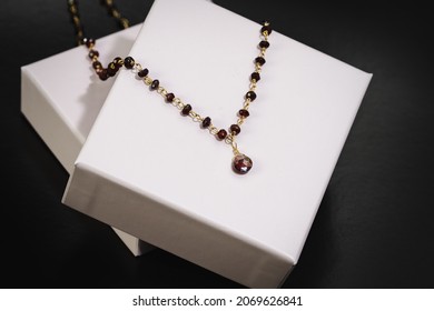 A gold necklace set with red stones on a black background