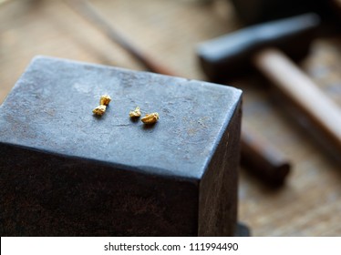 Gold Nuggets On A Old Anvil, With Tools In Background.