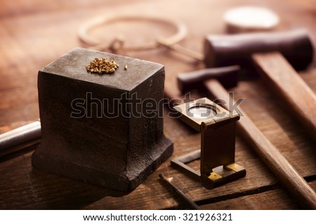 Gold nuggets on a old anvil, with tools in background. intentionally shot in nostalgic tone. Shallow depth of field.