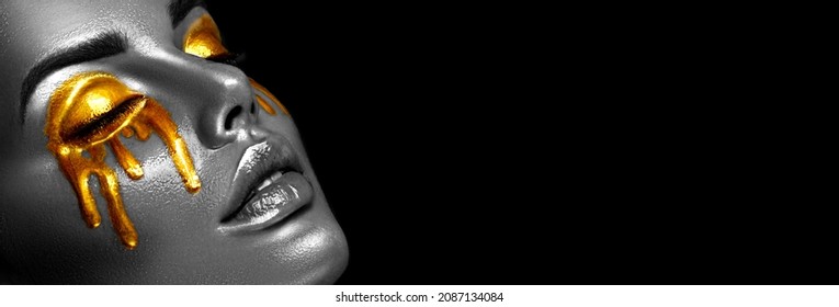 Gold Paint smudges drips on the face and eyes, dripping. Sexy lips, golden liquid drops on beautiful model girl's face, gold metallic tears, make-up. Beauty woman makeup close up. Black and white 