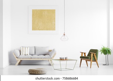 Gold Painting Above Grey Sofa In Bright Living Room With Armchair At Table, Pouf And Fern