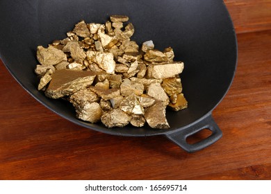 Gold Pan With Golden Nuggets Inside On Wooden Background