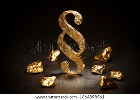 Gold paragraph sign and gold nuggets on black background.