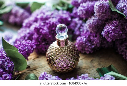 Gold perfumes bottle on wodoen table near purple flwoers. Oil.
