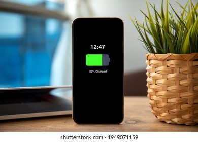 Gold Phone With Charged Battery On The Screen On Wooden Table In Office 