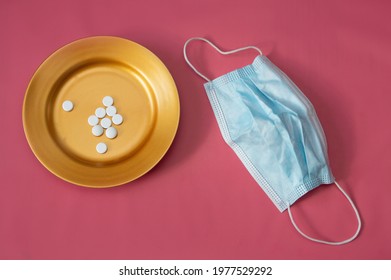 Gold Plate With Pills And Medical Mask On Pink Background