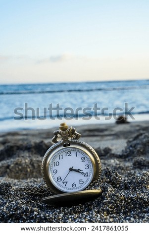  a gold pocket watch on beach sand, with the rhythmic dance of beach waves in the background